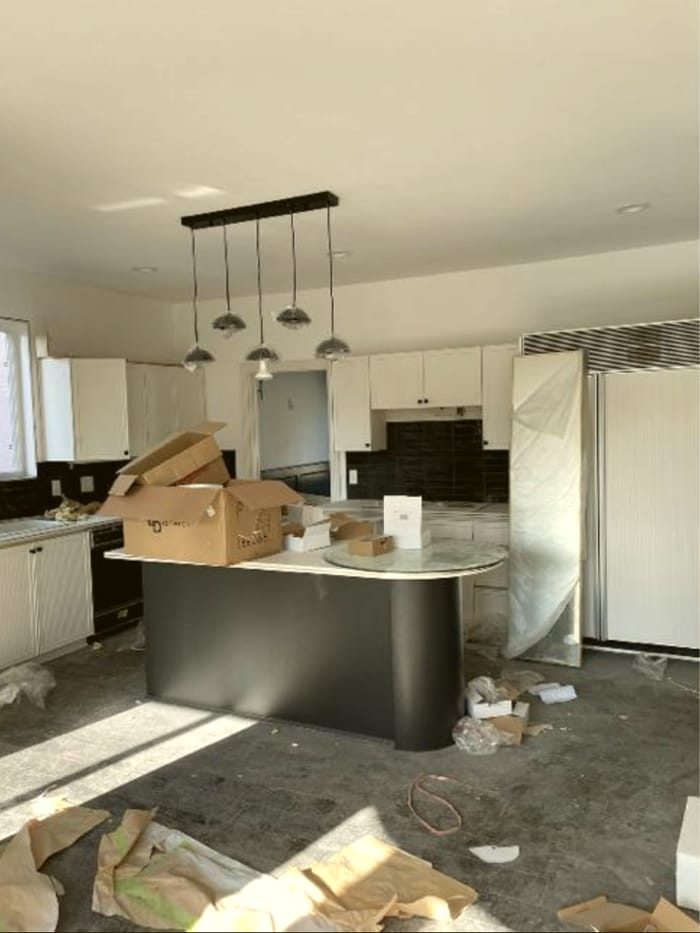 Kitchen mid move-in, with moving boxes and protective plastic wrap on the fridge